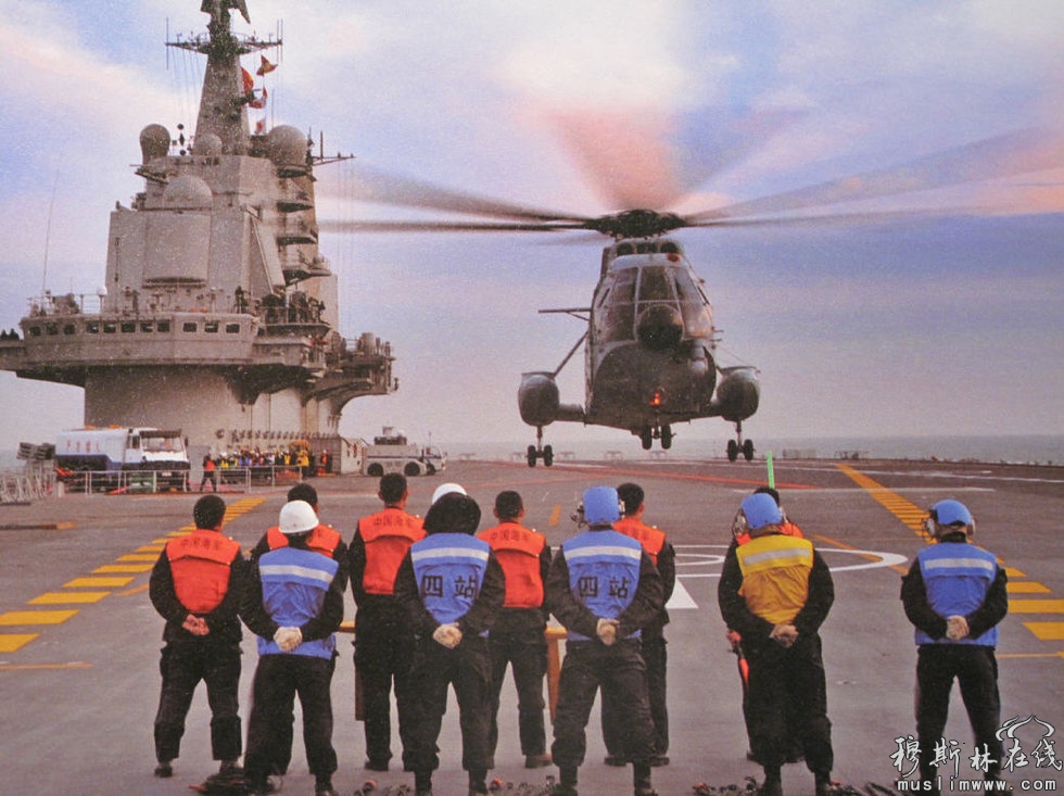 图为直8舰载直升机降落在辽宁号航母甲板上，引导直升机着舰的舰员穿上了带颜色标记的“马甲”。