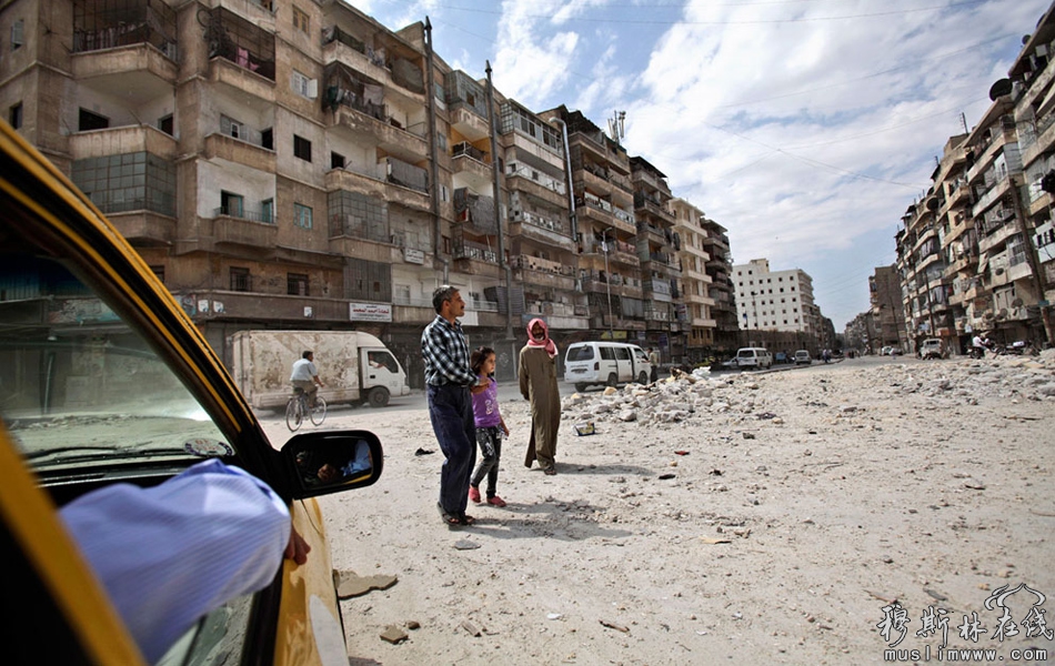 当地时间9月11日，阿勒颇，几名叙利亚人经过一片公寓废墟。 Muhammed Muheisen/摄