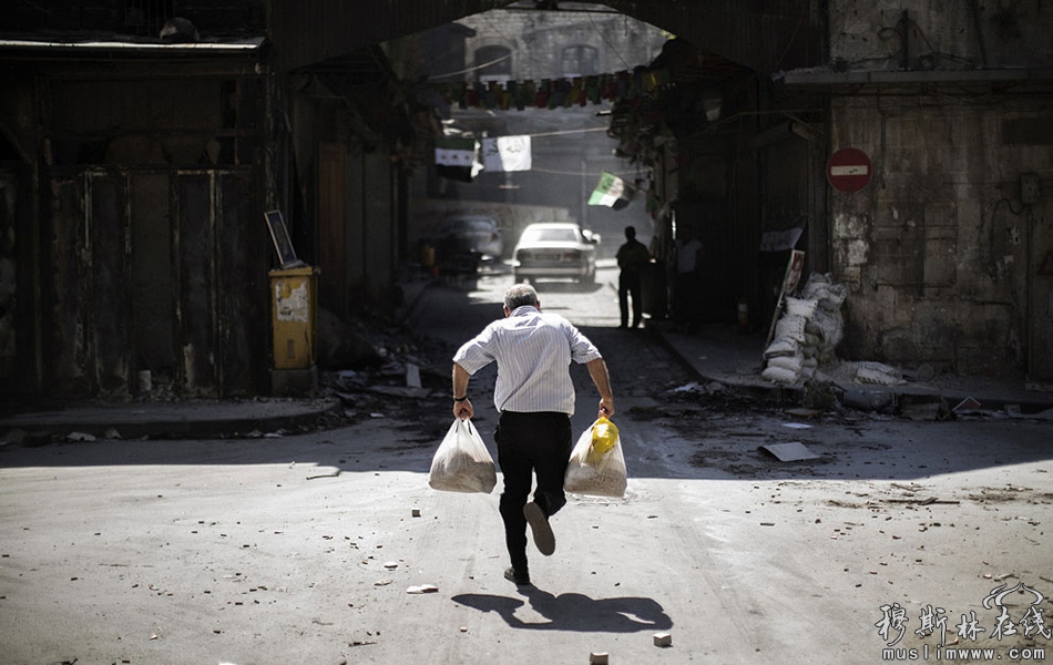 当地时间9月14日，一名叙利亚男子携带购物袋穿过阿勒颇一个检查站附近的一条小巷，试图躲避狙击手。 Marco Longari/摄