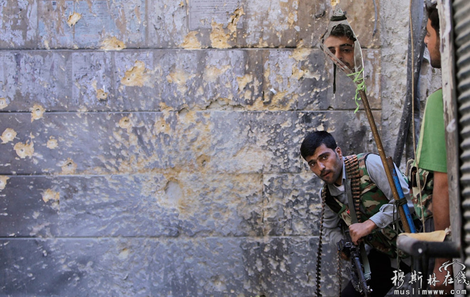 当地时间9月24日，阿勒颇，一场自由军与政府军的巷战中，一名隐蔽在转角处的叙利亚自由军战士借助一块镜子碎片查看政府军所处的位置。 Hussein Malla/摄
