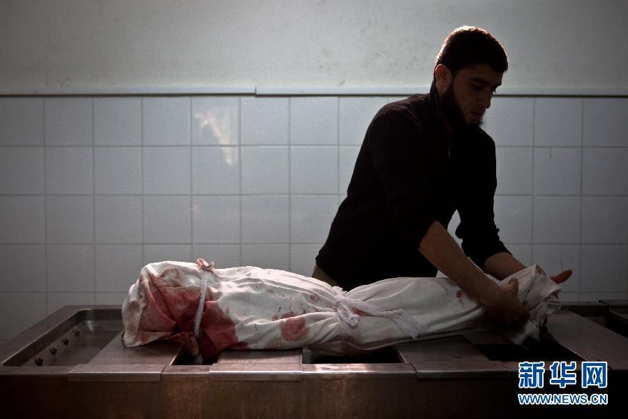 11月19日，在加沙城的希法医院，一名医院工作人员在整理达卢女儿的遗体。陈序 摄 图片来源：新华网 