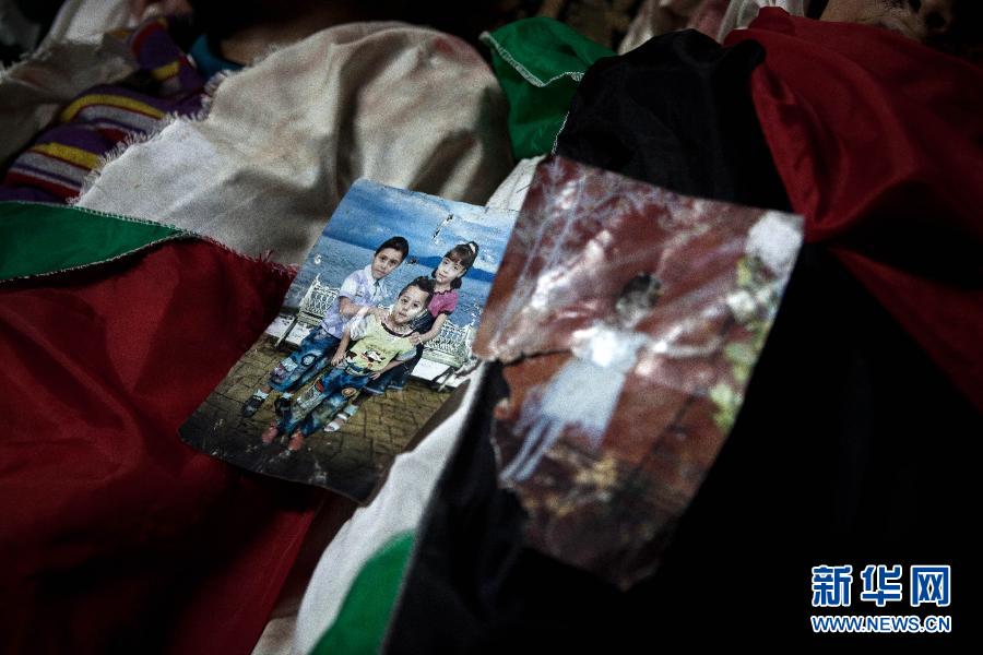 11月19日，在加沙城的希法医院，达卢子女的照片被放置在他们的遗体上。陈序 摄 图片来源：新华网 