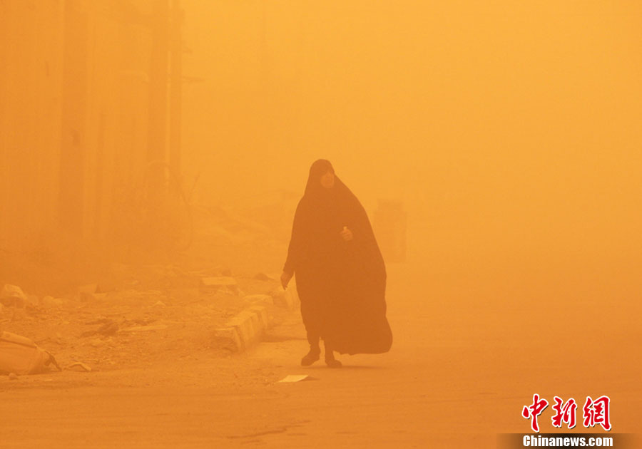 当地时间2012年5月22日，伊拉克巴格达，一名妇女走在黄沙飞舞的大街上。伊拉克遭遇特大沙尘暴，首都机场被迫关闭。图片来源：东方IC 