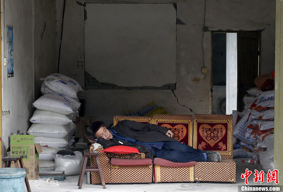 4月21日，四川雅安地震重灾区芦山龙门乡，一位老大爷在房间里的一张沙发上睡着了，并没有理会余震的影响。中新社记者 张浩 摄