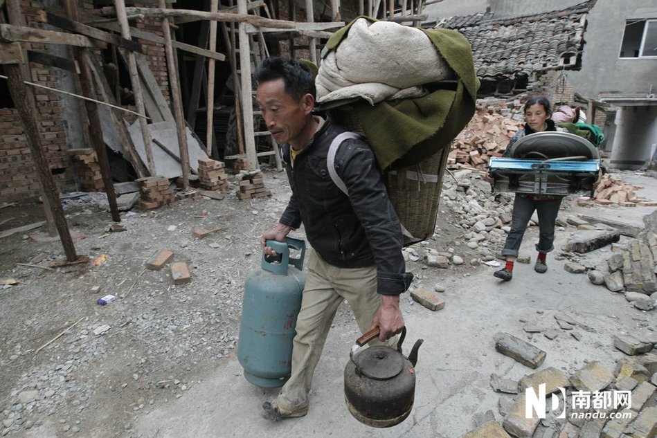 4月21日，龙门乡，余震不断，灾民返回家中收拾煤气炉、煤气瓶、水壶等家当，随后步行至救灾帐篷点。南都记者 谭庆驹 摄