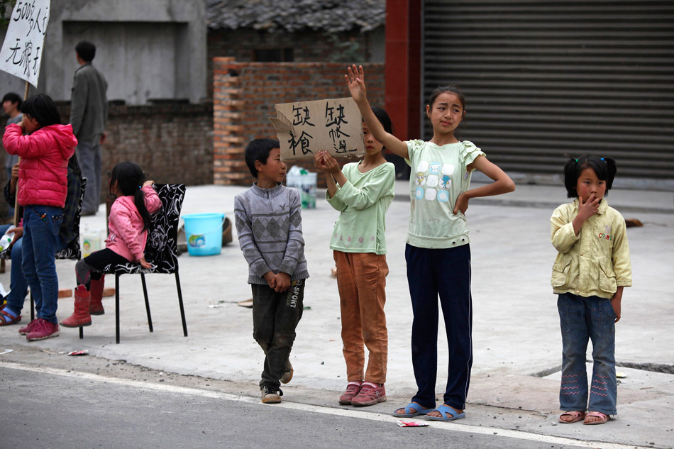 芦山县，孩子在路边打出缺乏物资的标语。