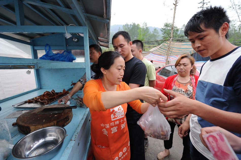 4月21日，凌贵芳（左）在芦山县城临时安置点销售祖辈经营的“凌家卤肉”。新华社记者 李健 摄