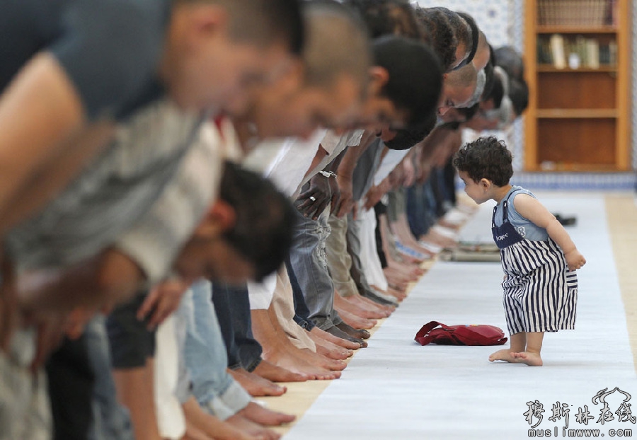 2013年7月9日斋月的第一天，法国斯特拉斯堡大清真寺一名小孩经过穆斯林在做午时祈祷。