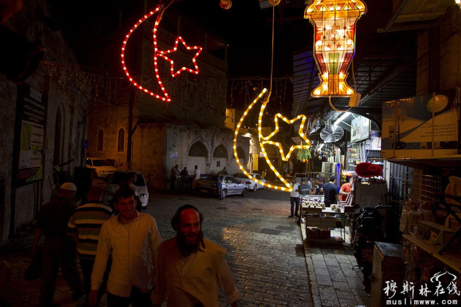 　2013年7月7日，耶路撒冷老城，一名犹太教男子走过悬挂着的斋月装饰品。斋月即将到来，人们已经做好了准备。