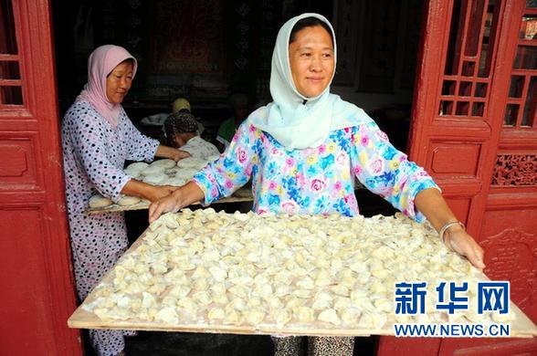 8月8日，在山东省临沂市郯城县马头镇清真寺，两名穆斯林妇女端着美食走出大殿。 当日是穆斯林的传统节日开斋节，郯城县穆斯林群众集体庆祝佳节，分享美味佳肴。 　　新华社发（房德华 摄）