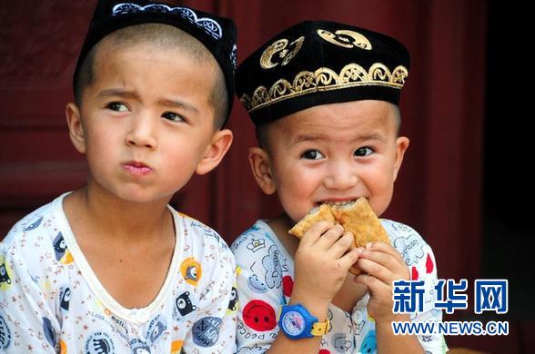 8月8日，在山东省临沂市郯城县马头镇清真寺，两名穆斯林妇女端着美食走出大殿。 当日是穆斯林的传统节日开斋节，郯城县穆斯林群众集体庆祝佳节，分享美味佳肴。 　　新华社发（房德华 摄）