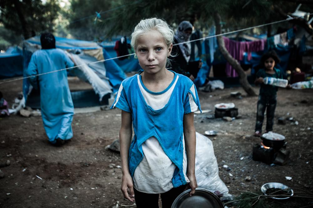 6、 住在土耳其的一个叙利亚女孩，手拿准备开斋饭的一个空盘。这个难民营设在公园里，接收新来的难民，因正式的难民营早已爆满。一些家庭在极为恶劣的状况下已经生活好几个月了。