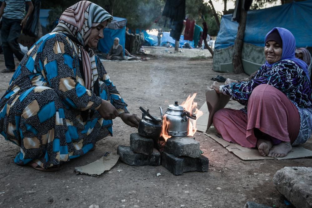 11、住在临时难民营的叙利亚妇女用纸箱生火来烧茶水。