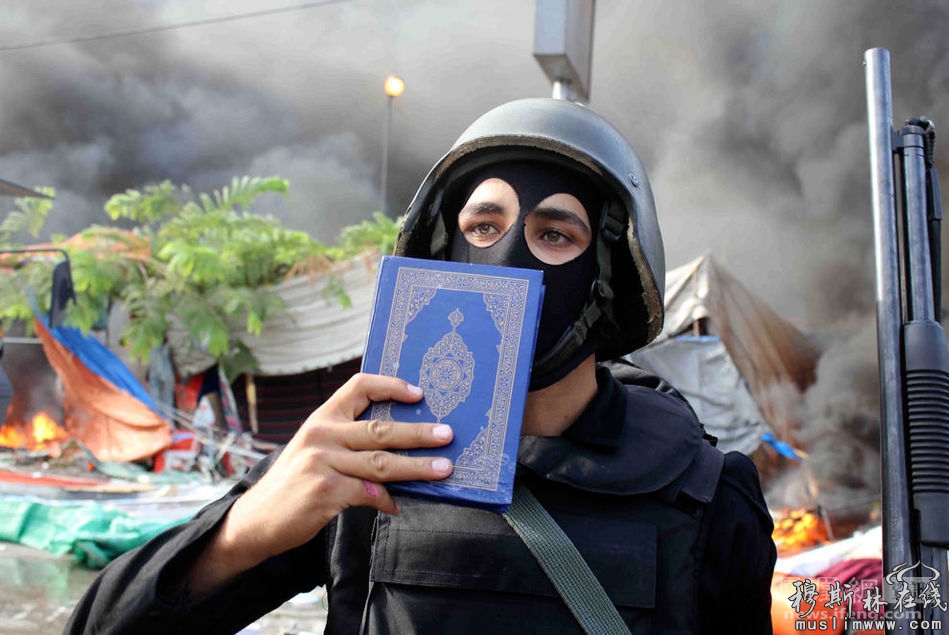 图为清场行动中，一名安全人员拿着一本《可兰经》。